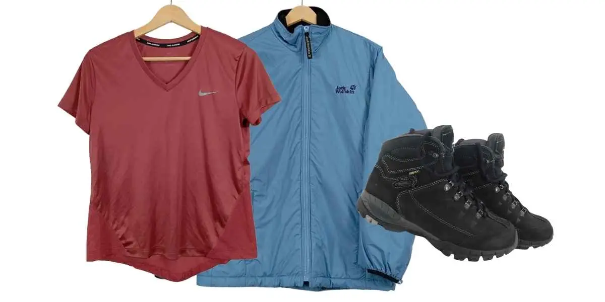 Rotes Sportshirt, blaue Outdoorjacke und schwarze Wanderschuhe